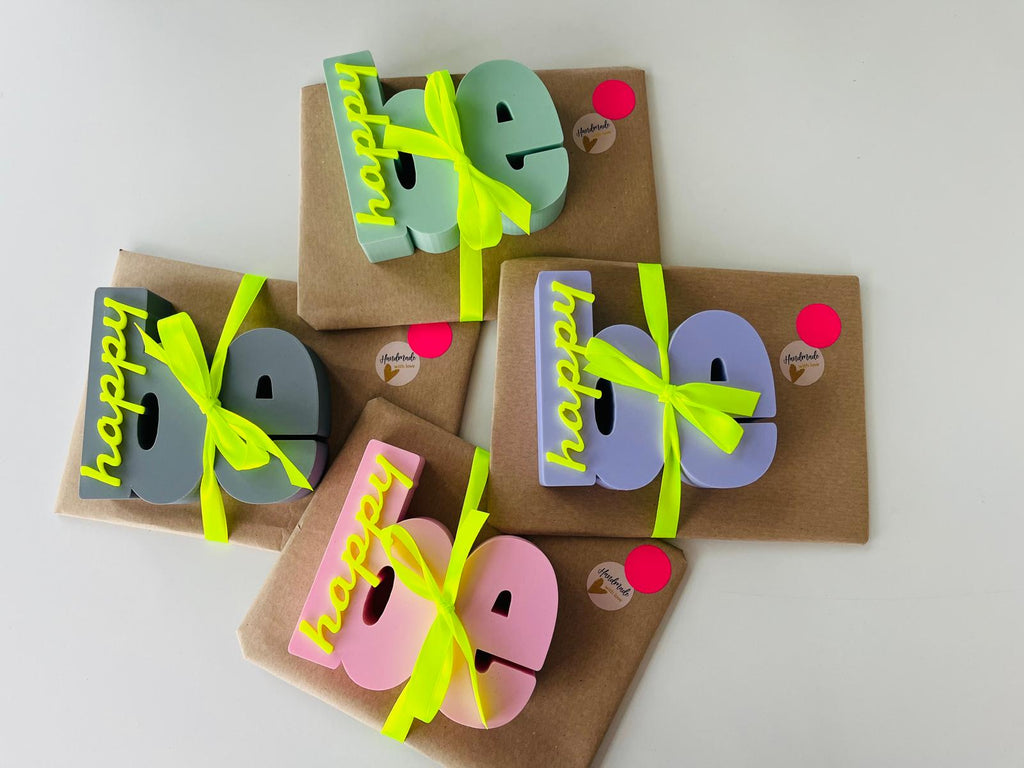 bymelli schriftzug "be happy" deko in verschiedenen farben verpackt als geschenk